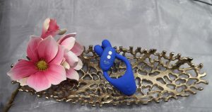 Doppio 2.0 in blau auf einer goldenen ovalen Schale mit einer rosa Blüte dekoriert